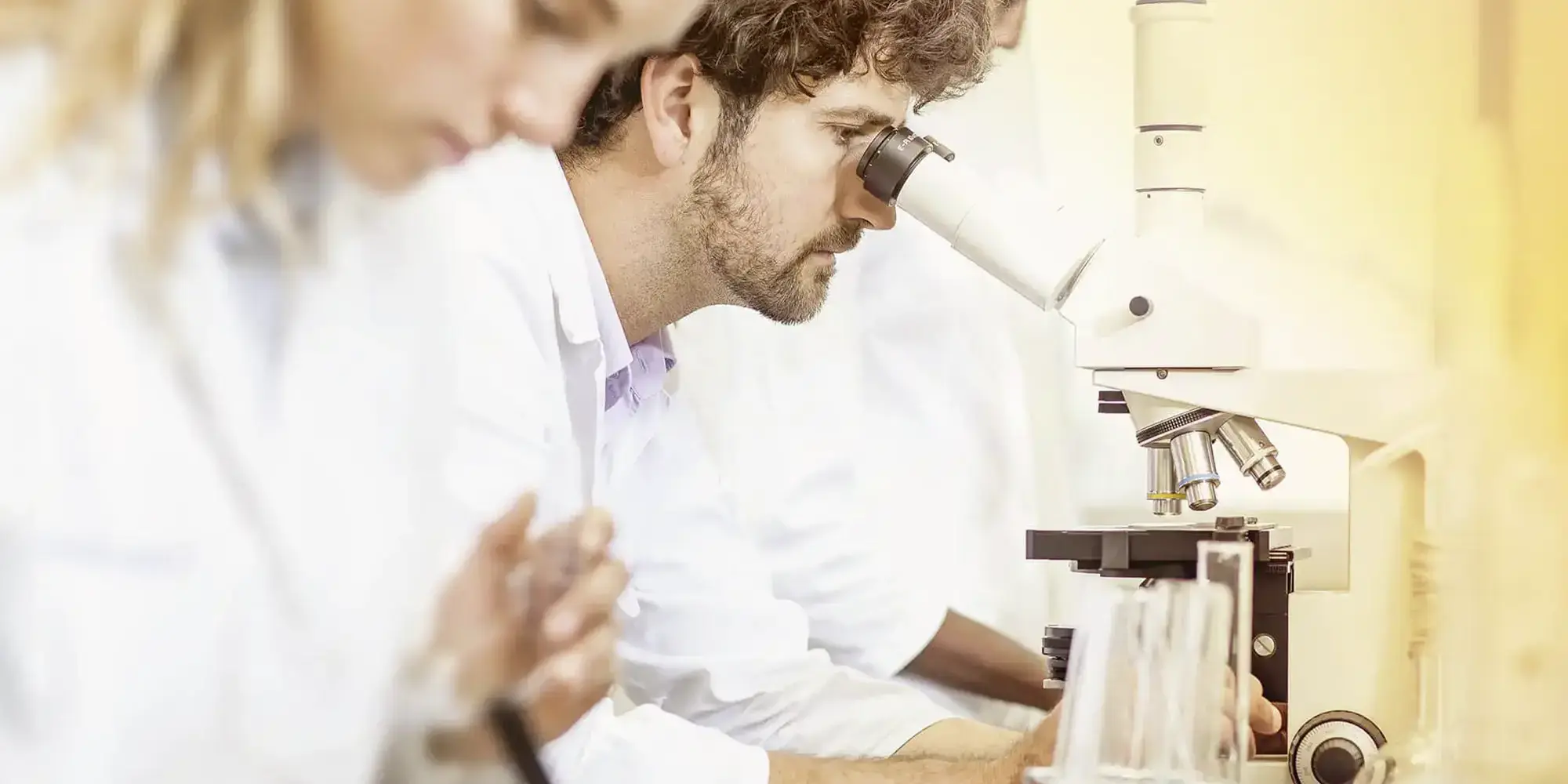 Symbolbild für Brandschutz-Services Forschung und Entwicklung bei svt: Mitarbeiter:innen in einem Labor mit Mikroskop.